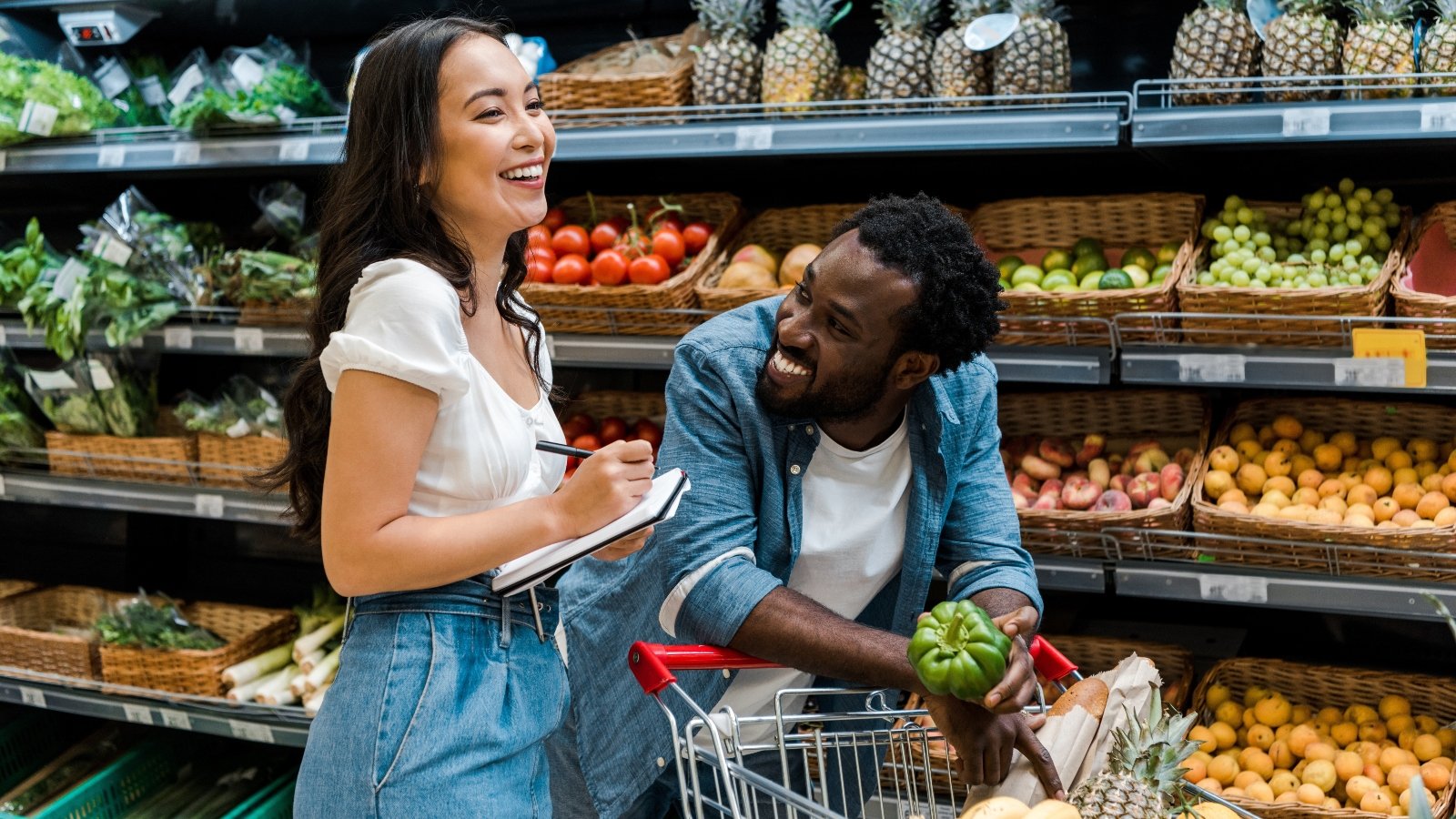 A couple laugh as they shop in the vegetable aisle
