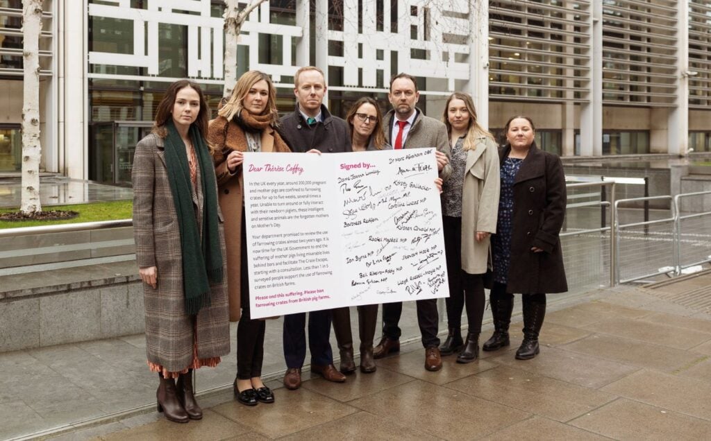 Animal rights campaigners holding a 'mother's day card' urging the uk government to ban pig farrowing crates