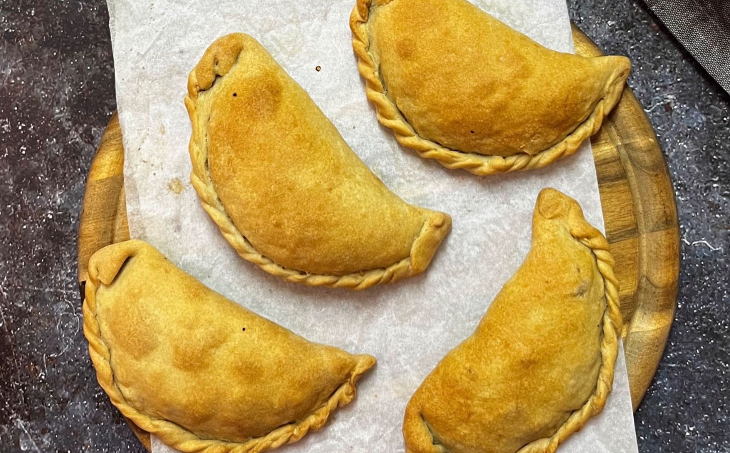 Vegan kolokotes pumpkin pies arranged on a wooden board, fresh out of the oven