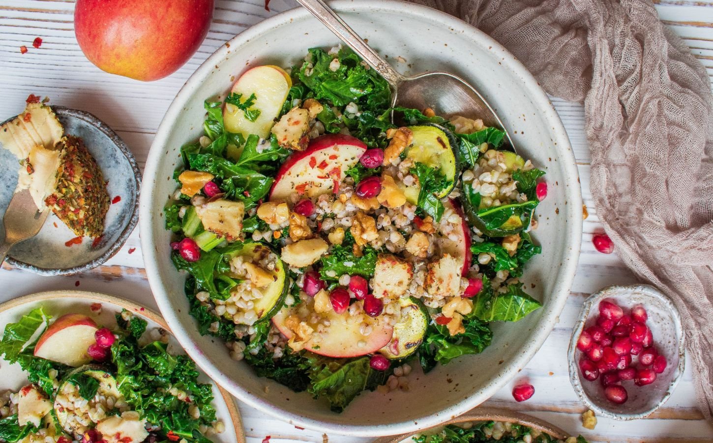 A vegan kale salad with apple, cashew cheese, and pomegranate