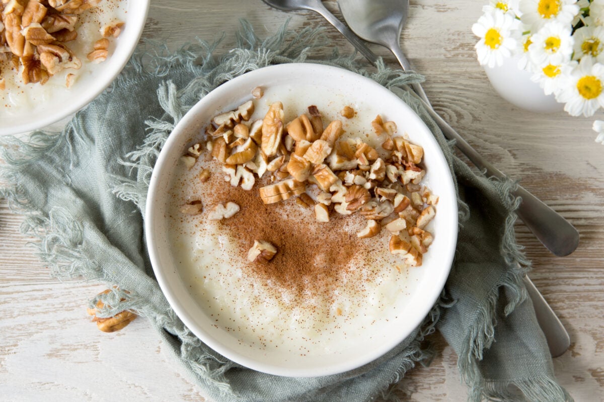 A bowl of oatmeal topped with pecans, walnuts, and cinnamon