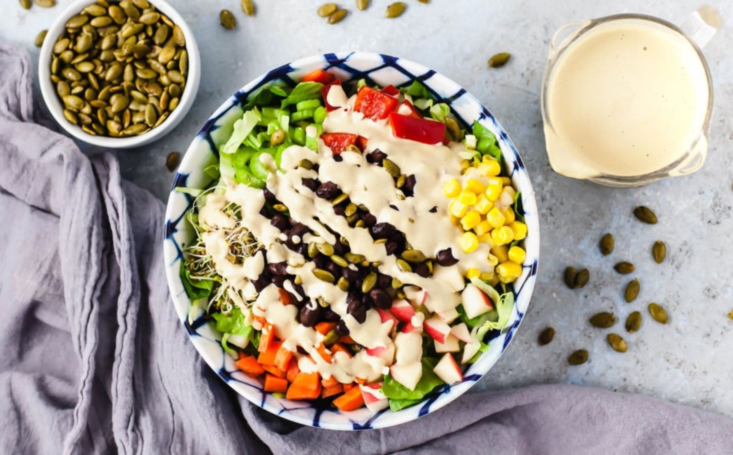 a vegan delicious salad made with lettuce, black beans, corn, vegan Caesar dressing, sprouts, and bell pepper